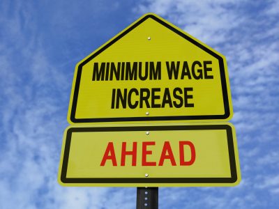 conceptual sign with words minimum wage increase  ahead over blue sky
